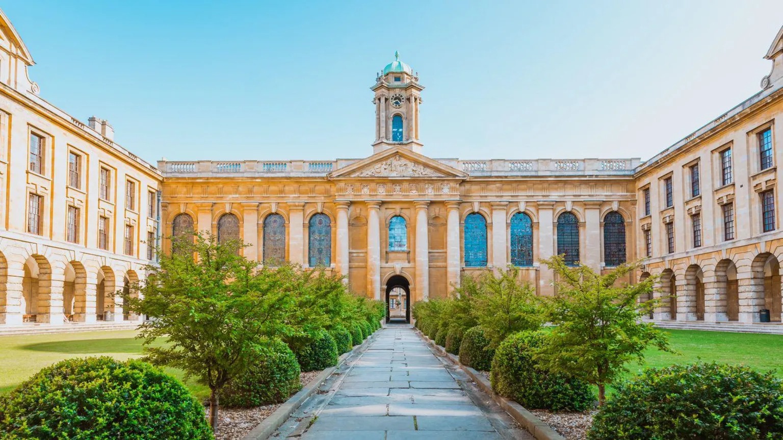 A college quadrangle with a lawn under a blue sky